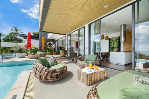 Covered poolside terrace with rattan seating and open-plan living access at Villa Yoco, Koh Samui