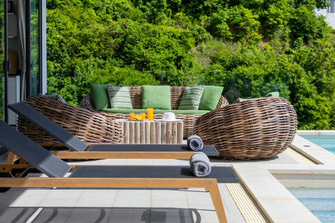 Poolside rattan sofa with cushions and tropical greenery at Villa Yoco, Koh Samui