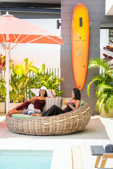 Guests relaxing on a rattan daybed in the tropical garden at Villa Yoco, Koh Samui