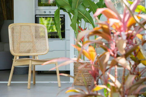 Indoor-outdoor living space with rattan furniture and tropical plants at C Villa, Koh Samui