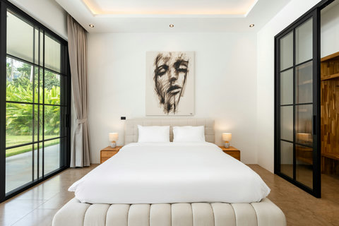 This inviting guest bedroom has a plush queen bed with soft headboard, natural wood touches, and direct access to the outdoor spaces. A peaceful room for rest