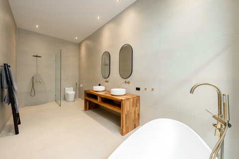 Step into calm. This bathroom pairs clean lines with warm wood tones and a spa-quality rainfall shower for a peaceful start to your day.