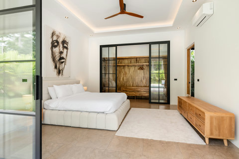 Settle into this serene bedroom with garden light pouring through full-length glass doors. A comfortable queen bed and wooden furnishings create a calm retreat