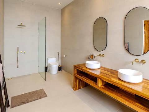 A spa-like ensuite where you and a travel companion each get your own round sink on a natural wood countertop. Rainfall shower and rainfall overhead are pure luxury