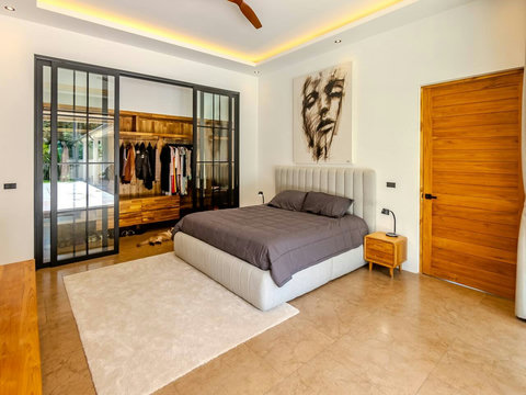 Wake up in this serene bedroom with soaring wooden beams overhead and green garden views through the sliding glass doors. Plenty of storage in the glass wardrobe