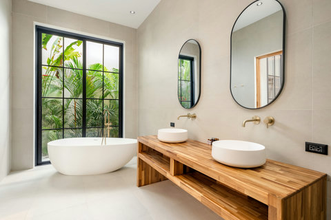 Soak in the freestanding tub with garden views, wood and ceramic finishes around you, natural light flooding through the doors.
