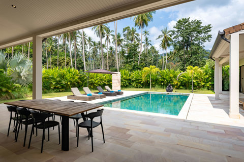 Settle in under the covered terrace with your group, dine together at the wooden table, and watch the palms sway beyond the pool.