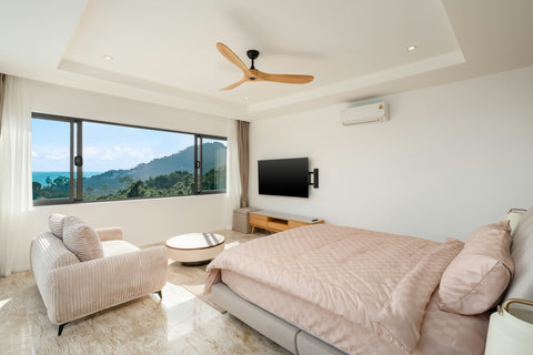 Bright and spacious bedroom with panoramic sea view, smart TV, and balcony access for a peaceful morning retreat.