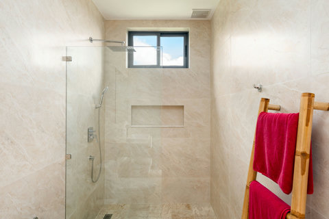 Modern ensuite bathroom with walk-in rain shower and warm stone finishes — elegant comfort throughout Villa Gala.
