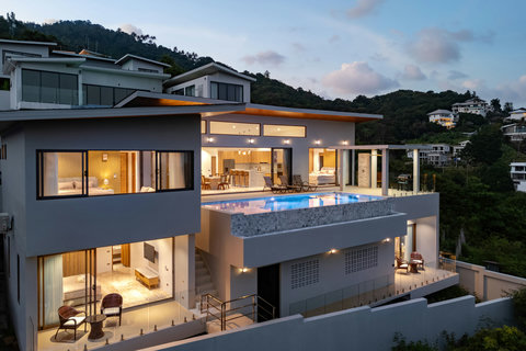 Villa Gala at sunset — modern architecture, infinity pool, and glowing warm lights overlooking Chaweng Noi’s hills.