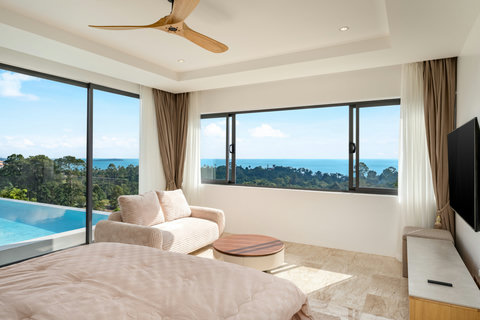 Wake up to blue skies and palm-dotted hills — this villa bedroom offers direct pool and sea views for the perfect start to the day.