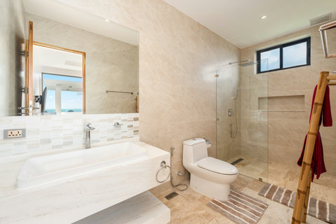 Spacious ensuite bathroom with bathtub, walk-in shower, and ocean view — elegant comfort in every detail.