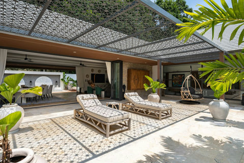 Shaded outdoor lounge with elegant daybeds and lush tropical garden surroundings