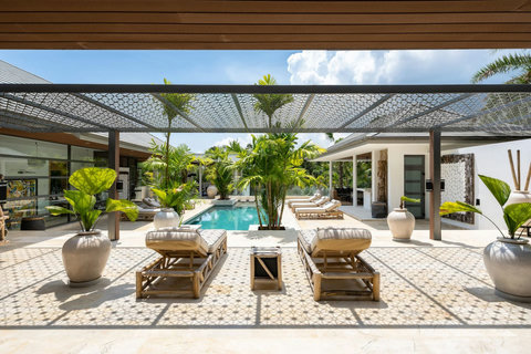 Covered wooden terrace with comfortable seating and views over the pool and garden