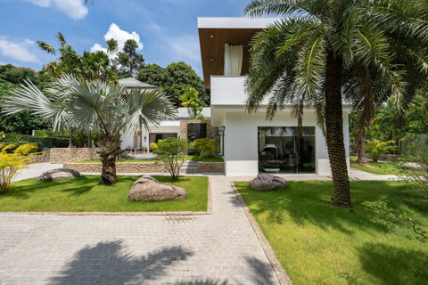 Impressive villa entrance with stone accents, landscaped courtyard, and palm trees