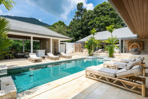 Inviting poolside with cushioned sun loungers and panoramic views of the villa grounds