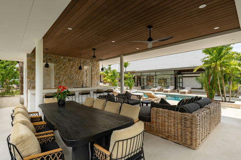 Stylish covered outdoor dining pavilion with wicker furnishings and poolside ambiance