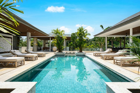 Crystal-clear swimming pool flanked by sun loungers and tropical palm trees