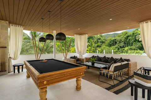 Covered outdoor terrace with pool table and stunning tropical hillside views