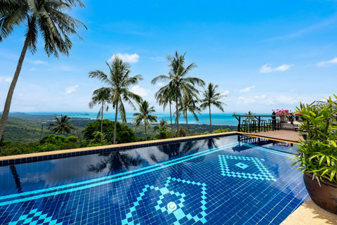 Tranquil blue-tiled pool framed by tropical palms and ocean panorama