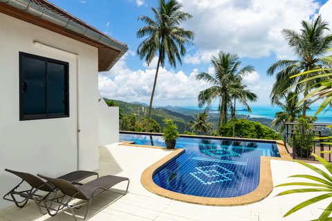 Crystal-clear infinity pool overlooking lush tropical hills and turquoise waters