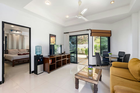 Open-plan living room with sofa bed for a second sleeping area, flat-screen TV, and modern decor in Koh Samui bungalow