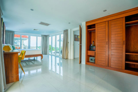 Open-plan living and dining area with polished wooden floors and Thai decor