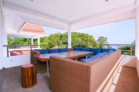 Covered outdoor dining terrace with ceiling fan and garden views