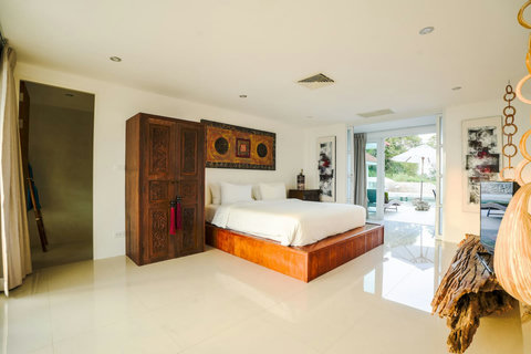 Serene white bedroom with queen bed and warm wooden accent furniture