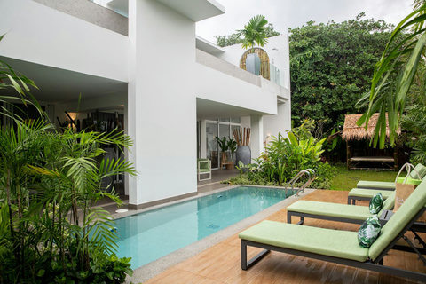 Villa exterior and pool area with loungers set in a private tropical garden at C Villa, Koh Samui