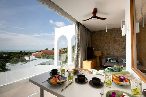 Open-plan living and dining area with stone walls and garden views at C Villa, Koh Samui private retreat