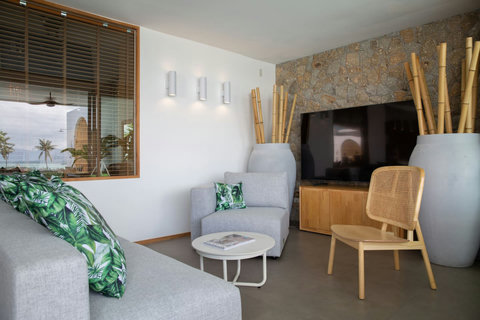 Cozy reading corner with rattan armchair and natural stone feature wall at C Villa, Koh Samui villa