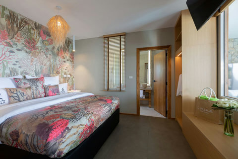 Vibrant guest bedroom with tropical floral accent wall and ceiling fan at C Villa, Thailand vacation rental