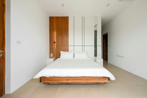 Minimalist bedroom with artistic wood wall feature Mark Marlow Samui