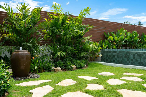 Lush green lawn with decorative pot and stepping stones Samui villa