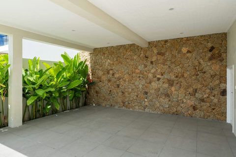 Secure covered parking with a natural stone feature wall and tropical greenery on arrival.