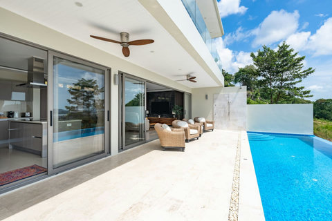 “Poolside lounge with shaded seating and ceiling fans, designed for comfort in the tropical climate