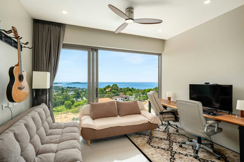 Multi-functional room with dual workstations, a comfortable sofa, and guitars on the wall – ideal for work or leisure.