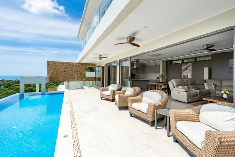 Spacious open living and dining area with direct pool access and stunning hillside backdrop.