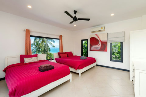 Spacious twin bedroom with ocean glimpses and tropical garden views.