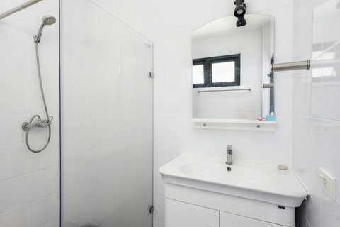 Modern white-tiled bathroom with walk-in shower and clean design