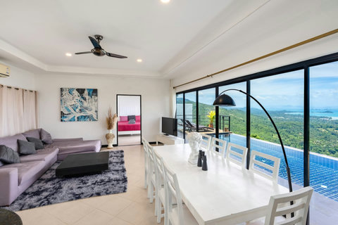 Open-plan dining and lounge with floor-to-ceiling windows overlooking the private pool and ocean.