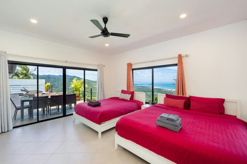 Spacious guest bedroom with twin beds and panoramic views over Nathon Bay.