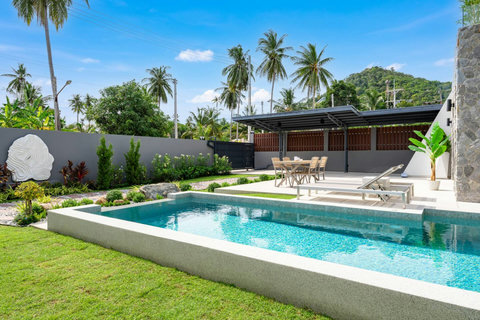 Spacious private swimming pool with tropical garden views and sun loungers at Villa Solaria