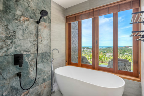 Open-air bathroom with freestanding tub and lush tropical views