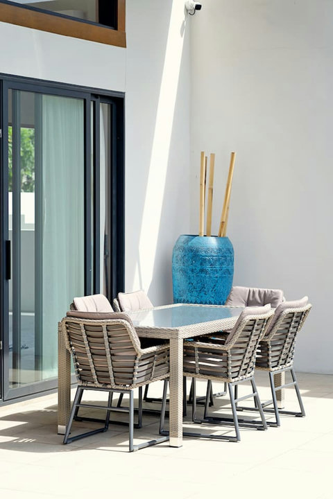 Outdoor dining area with rattan chairs and poolside garden setting