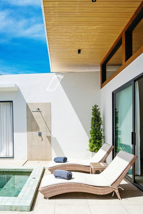 Modern white villa architecture with poolside sun loungers and tropical planting