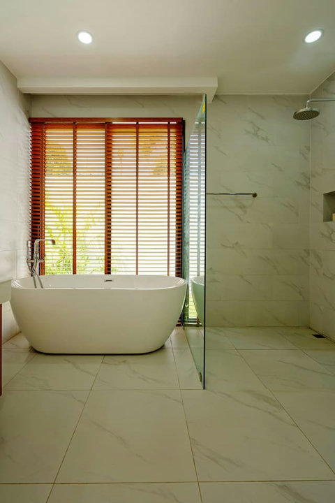 Ensuite bathroom with freestanding bathtub, rain shower and wooden shutters