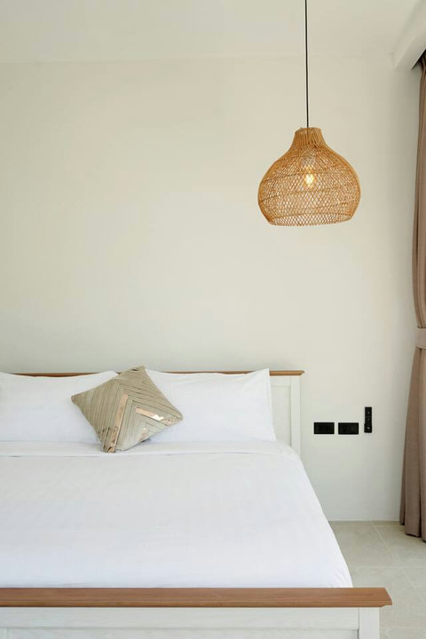 Comfortable bedroom with plush cushions and woven pendant lighting
