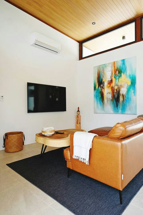Cozy living area with leather sofa, flat-screen TV and vibrant artwork